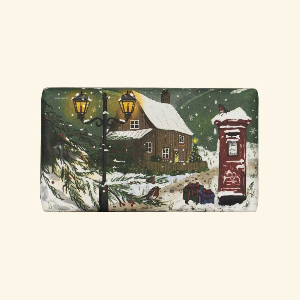 “Seife mit winterlicher Dorfszene: Haus, Schneelandschaft, Straßenlaternen und rotem Briefkasten.”