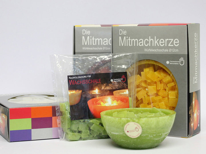 Set mit grüner Schalenkerze, Wachsgranulat, Verpackung „Mitmachkerze“ und Anleitung in Klarsichtbeutel, auf hellem Hintergrund.
