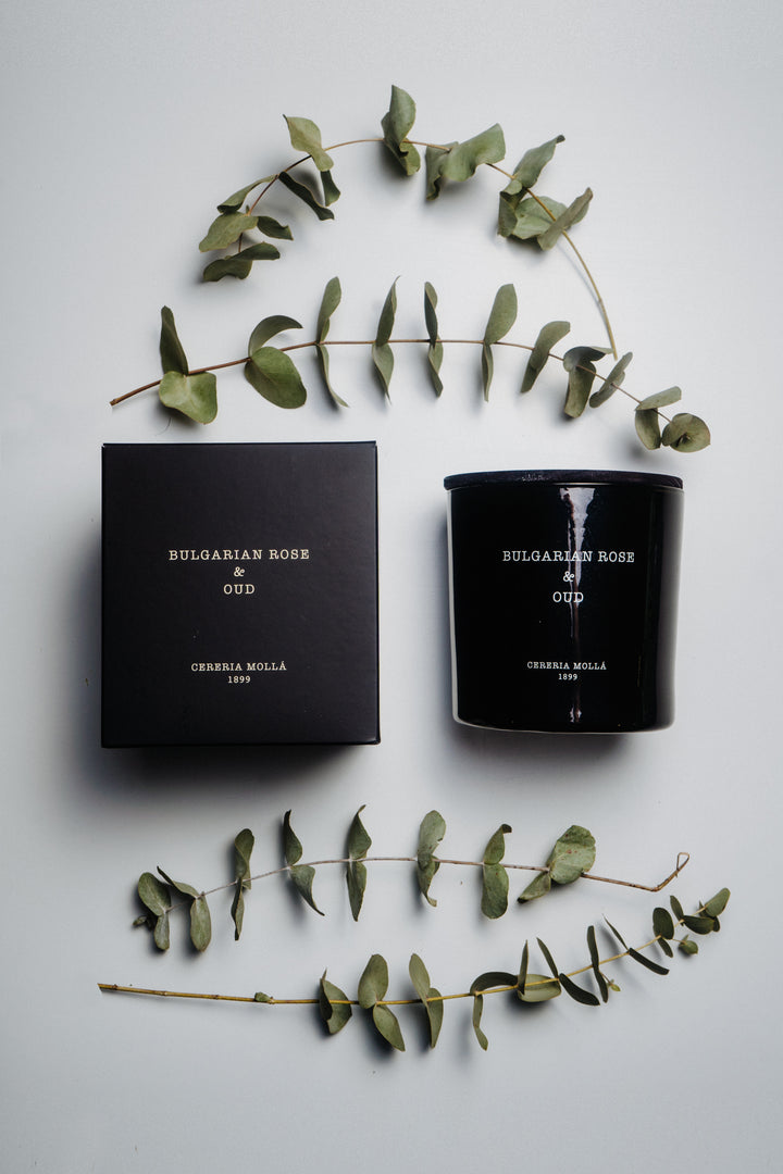 Schwarze Duftkerze Bulgarian Rose & Oud und passende Geschenkverpackung von Cereria Mollá elegant arrangiert auf hellem Untergrund. Umrahmt von frischen Eukalyptuszweigen – natürlich, luxuriös und stilvoll inszeniert
