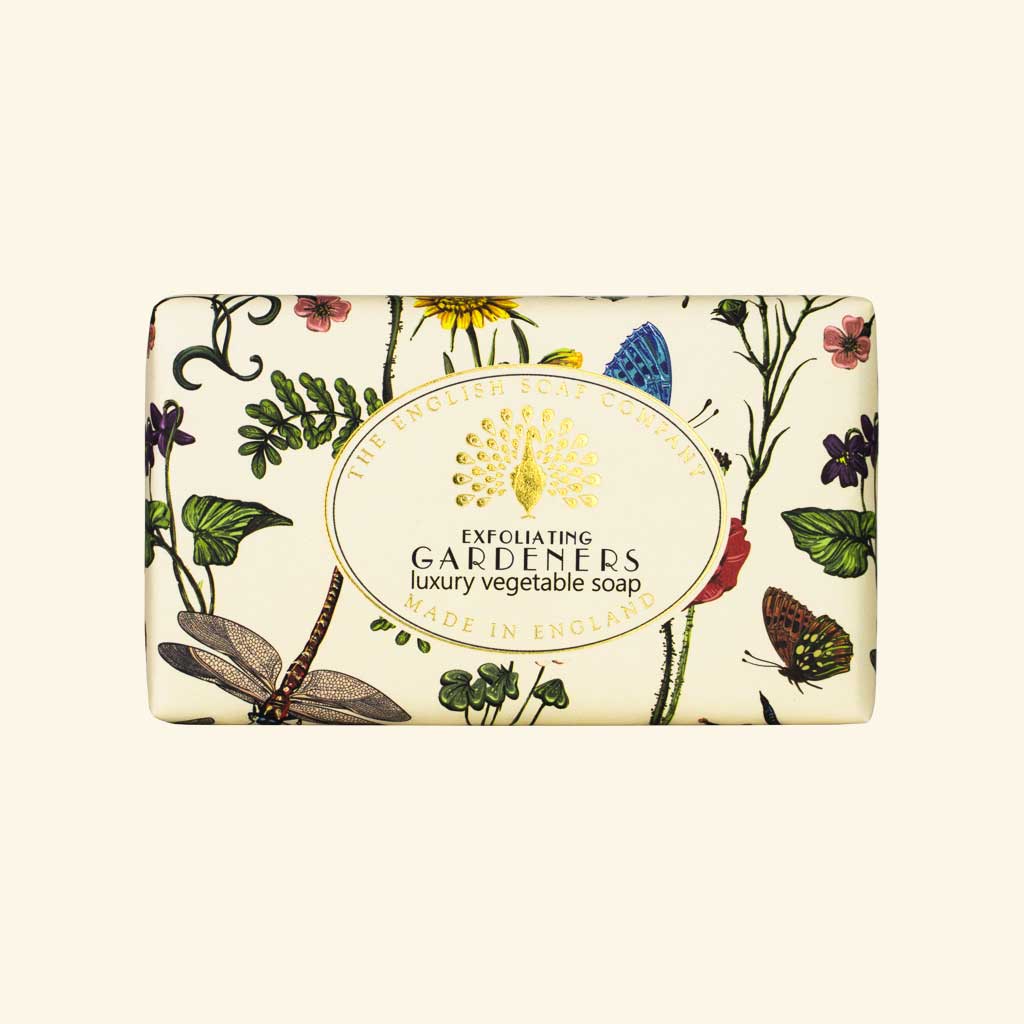 “Seife mit botanischen Illustrationen, Schmetterlingen und Libellen, Aufschrift ‘Exfoliating Gardeners – luxury vegetable soap’.”