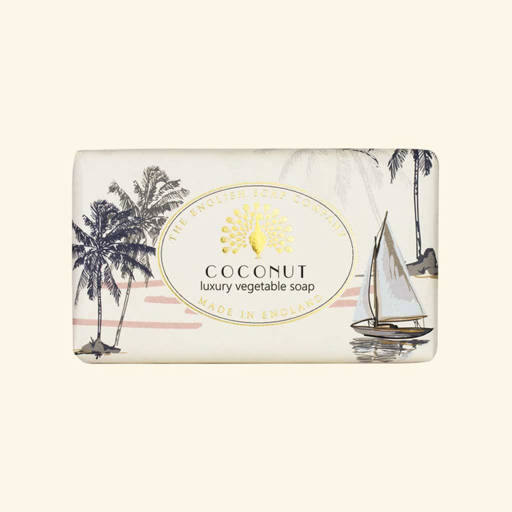 “Helle Seife mit tropischer Strandillustration, Palmen und Segelboot, Aufschrift ‘Coconut – luxury vegetable soap’.”