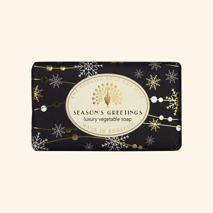 “Schwarze Seife mit goldenen Schneeflocken und Aufschrift ‘Season’s Greetings – luxury vegetable soap’.”