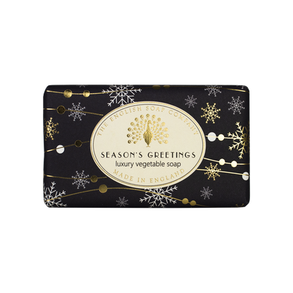 “Schwarze Seife mit goldenen und weißen Schneeflocken, Aufschrift ‘Season’s Greetings – luxury vegetable soap’.”