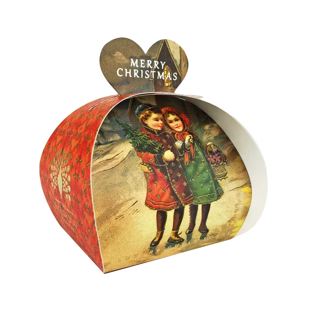 „Weihnachtsseife der Marke The English Soap Company in herzförmiger Geschenkverpackung mit rotem Seitenmotiv, Motiv: zwei Kinder mit Weihnachtsbaum im Vintage-Stil vor winterlicher Landschaft, Aufschrift: ‚Merry Christmas‘.“