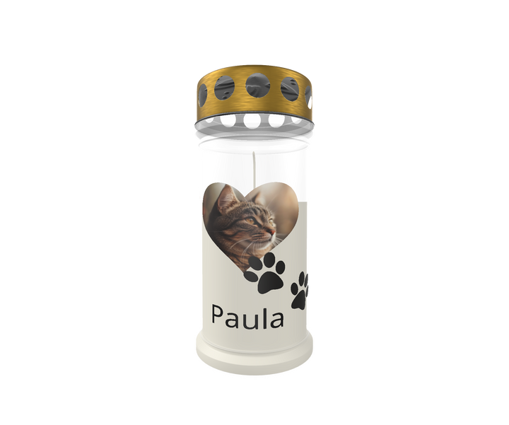 Weiße Gedenkkerze mit goldenem Deckel vor weißem Hintergrund. Auf der Kerze befindet sich ein herzförmiges Bild einer grau-getigerten Katze, darunter zwei schwarze Pfotenabdrücke. Der Name „Paula“ ist in klarer schwarzer Schrift darunter platziert. Das Design vermittelt liebevolle Erinnerung an ein verstorbenes Haustier.