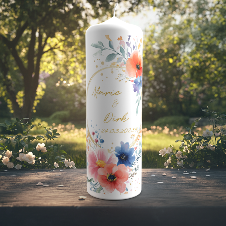 Eine farbenfrohe Hochzeitskerze steht auf einem Holztisch in einem sommerlich blühenden Garten. Das Design zeigt ein florales Aquarellmotiv mit Mohnblumen, blauen Kornblumen, Eukalyptus und weiteren zarten Blättern in fröhlichen Farben. In der Mitte stehen die Namen „Marie & Dirk“ in goldfarbener Schreibschrift sowie das Hochzeitsdatum „24.03.2023“. Goldene Sprenkel und ein geschwungener Halbkreis verleihen der Kerze eine verspielte, festliche Eleganz.