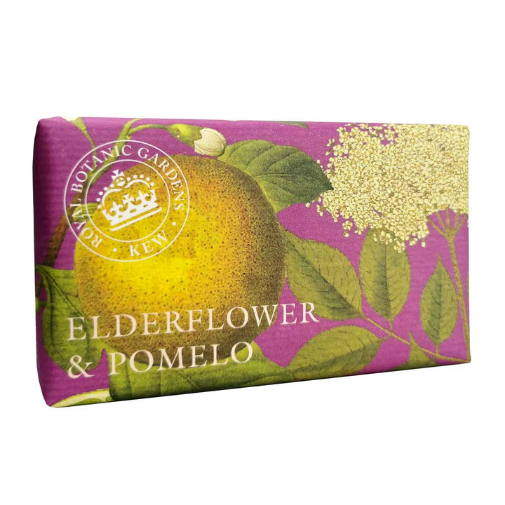 “Seife in edlem Papier mit Illustration von Holunderblüten und Pomelo auf violettem Hintergrund, Text: Elderflower & Pomelo.”
