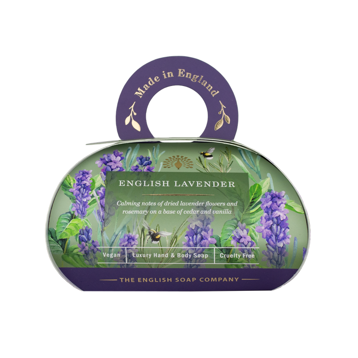 „Luxus-Hand- und Körperseife der Marke The English Soap Company in ovaler Verpackung mit Tragegriff, Motiv: Lavendelblüten, Bienen und Kräuter auf dunklem Hintergrund, Aufschrift: ‚English Lavender – Calming notes of dried lavender flowers and rosemary on a base of cedar wood and vanilla‘.“