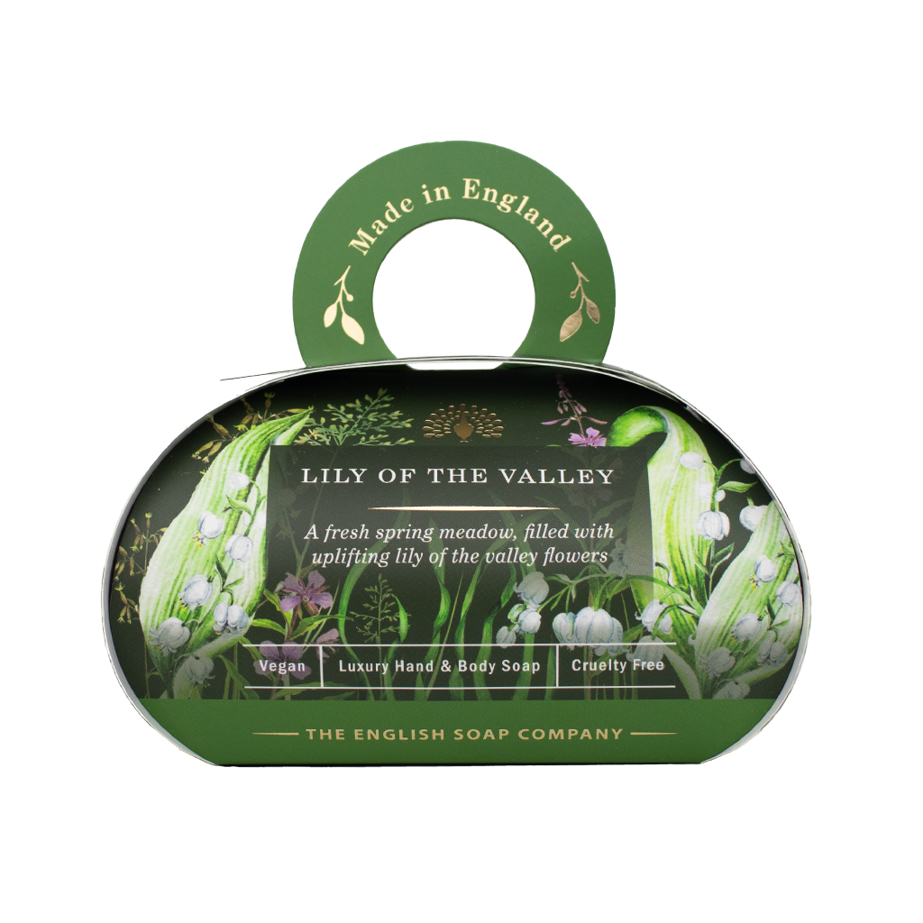 „Luxus-Hand- und Körperseife der Marke The English Soap Company in ovaler Verpackung mit Tragegriff, Motiv: Maiglöckchen und Frühlingsblumen auf dunklem Hintergrund, Aufschrift: ‚Lily of the Valley – A fresh spring meadow, filled with uplifting lily of the valley flowers‘.“