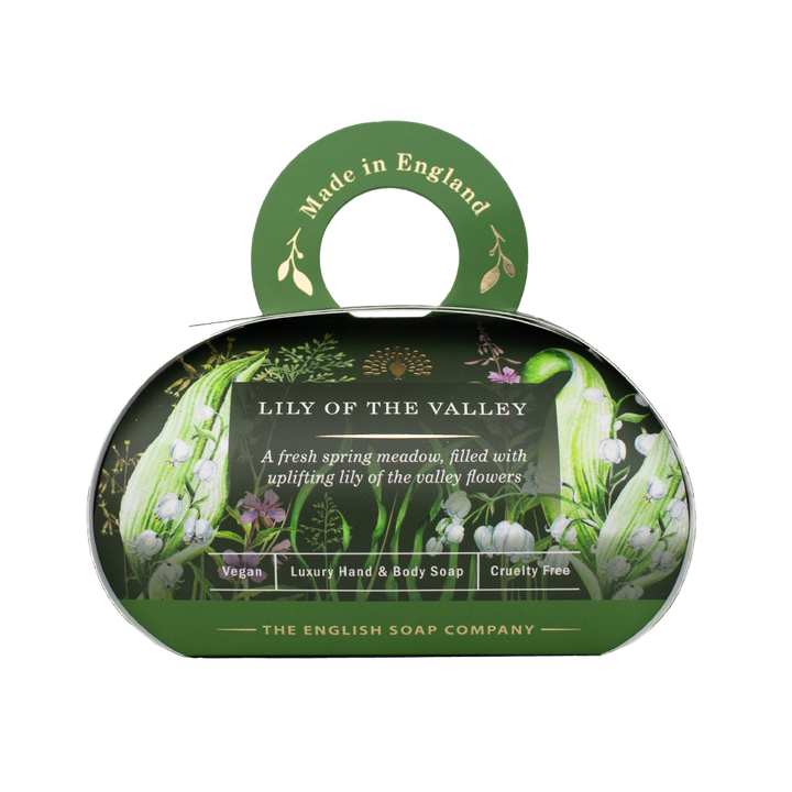 „Luxus-Hand- und Körperseife der Marke The English Soap Company in ovaler Verpackung mit Tragegriff, Motiv: Maiglöckchen und Frühlingsblumen auf dunklem Hintergrund, Aufschrift: ‚Lily of the Valley – A fresh spring meadow, filled with uplifting lily of the valley flowers‘.“