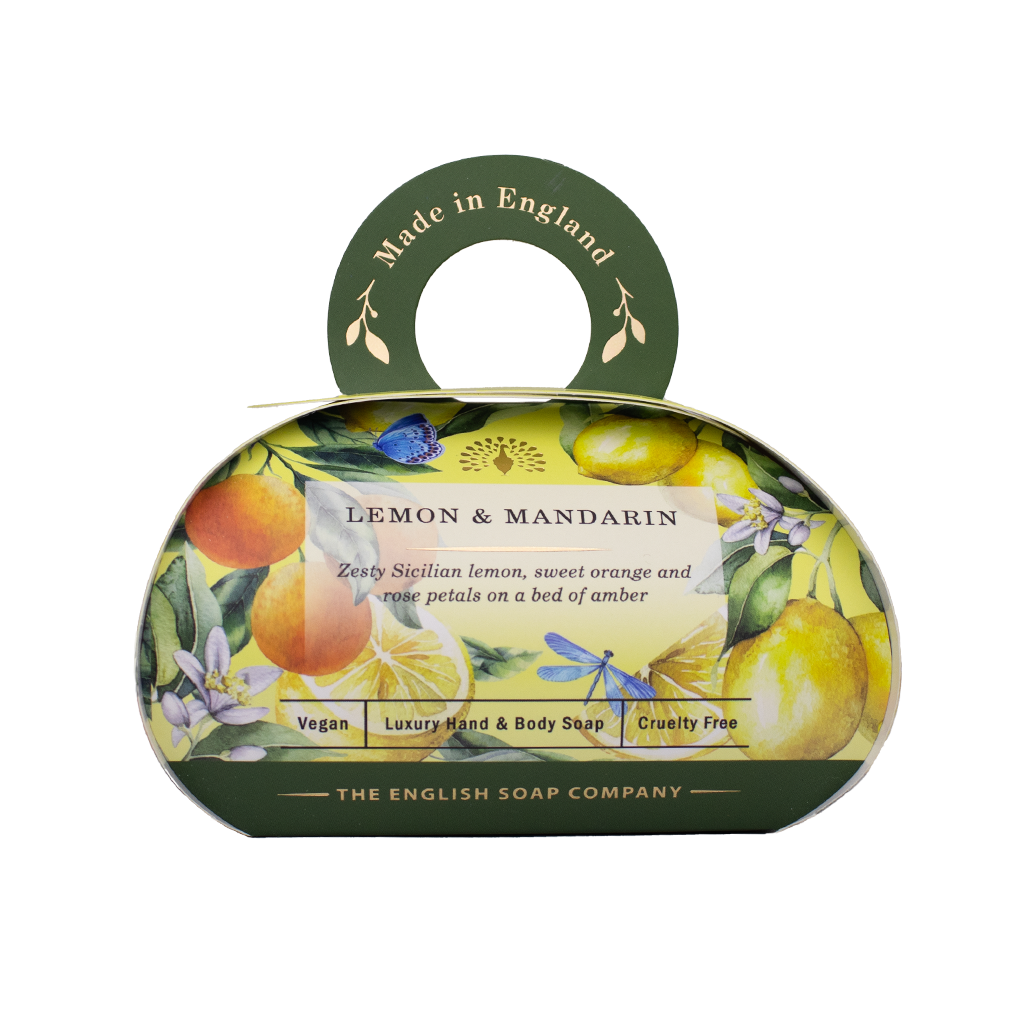 Luxus-Hand- und Körperseife der Marke The English Soap Company in ovaler Verpackung mit Tragegriff, Motiv: Zitronen, Mandarinen und Blüten, Aufschrift: ‚Lemon & Mandarin – Zesty Sicilian lemon, sweet orange and white petals on a bed of amber‘.