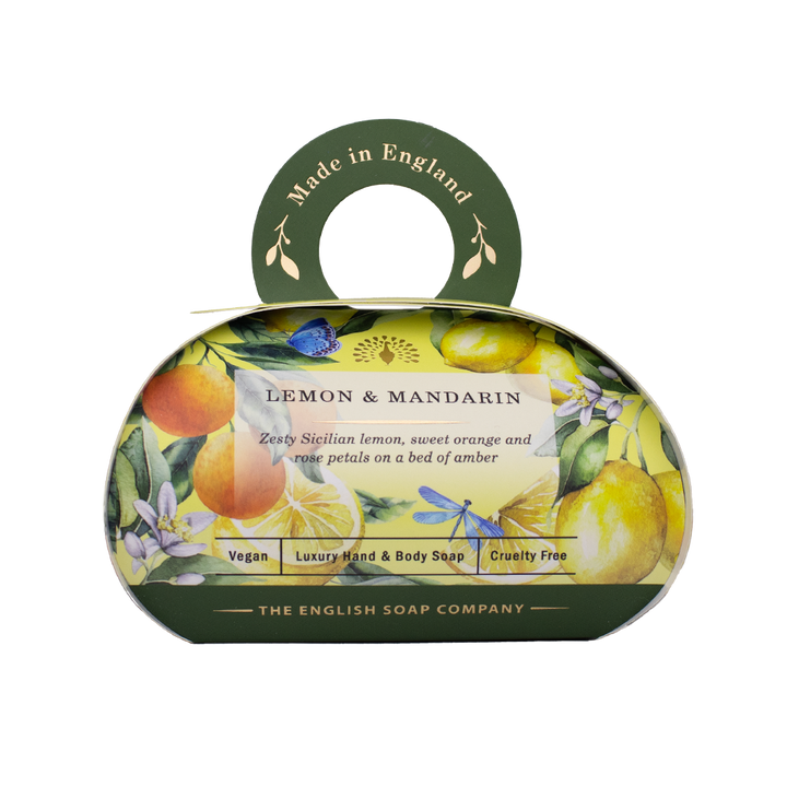 Luxus-Hand- und Körperseife der Marke The English Soap Company in ovaler Verpackung mit Tragegriff, Motiv: Zitronen, Mandarinen und Blüten, Aufschrift: ‚Lemon & Mandarin – Zesty Sicilian lemon, sweet orange and white petals on a bed of amber‘.