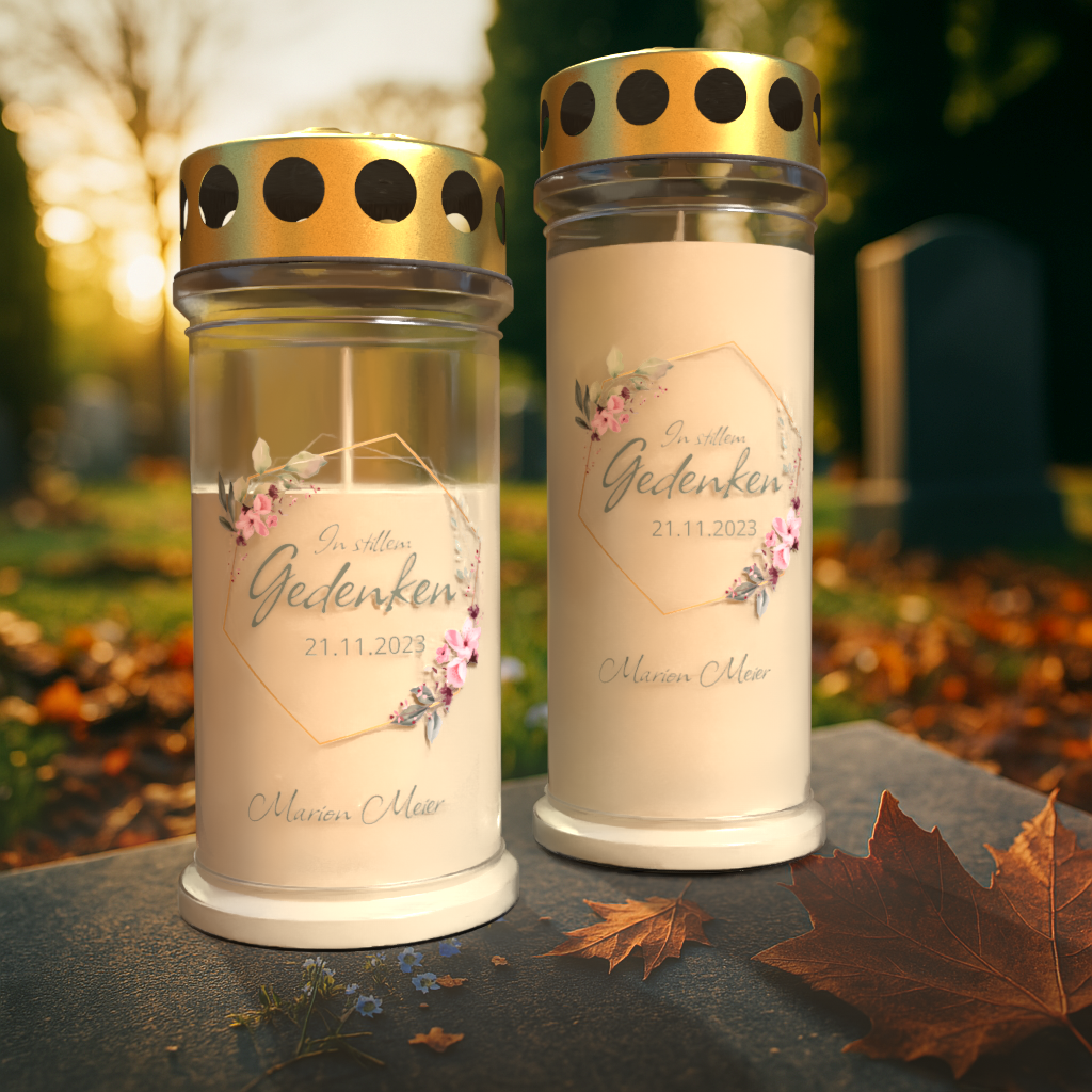 Personalisierte Gedenkkerze „In stillem Gedenken“ mit Name und Datum, Grablicht mit Blumenmotiv und goldenem Schutzdeckel auf Friedhof