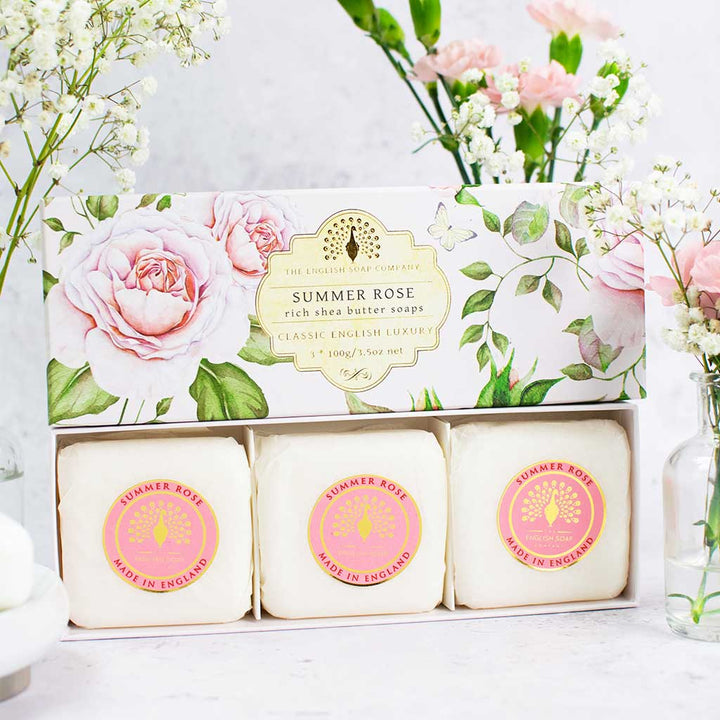 „Drei runde Seifenstücke der Sorte ‘Summer Rose’ in einer geschlossenen Geschenkbox mit rosafarbenem Blumendesign.“