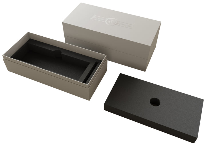 Rechteckige, stabile Aufbewahrungsbox mit Deckel und passgenauer Schaumstoffeinlage für den sicheren Transport oder die Aufbewahrung einer Kerze; die Box ist in neutralem Grau gehalten und mit einem geprägten Logo auf dem Deckel versehen