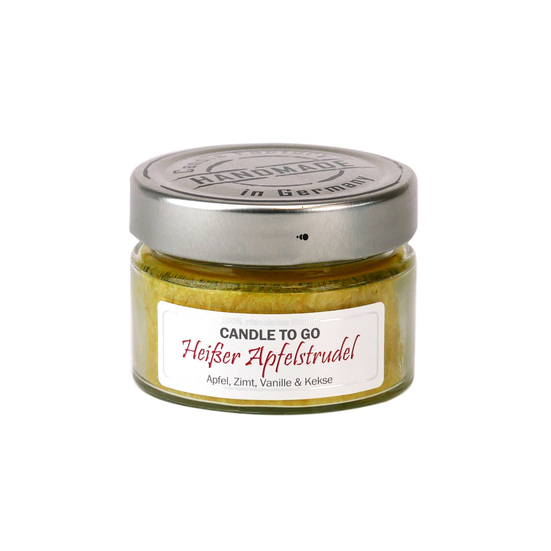 Kleine gelbe Duftkerze im Glas mit Metalldeckel und Etikett „Candle to go – Heißer Apfelstrudel“ auf weißem Hintergrund.