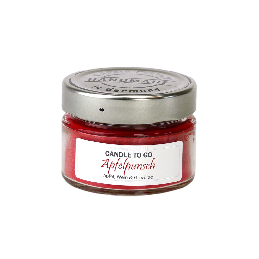 Kleine rote Duftkerze im Glas mit Metalldeckel und Etikett „Candle to go – Apfelpunsch“ auf weißem Hintergrund.