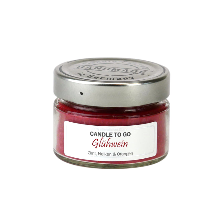 eine rote Duftkerze im Glas mit Metalldeckel und Etikett „Candle to go – Glühwein“ auf weißem Hintergrund.