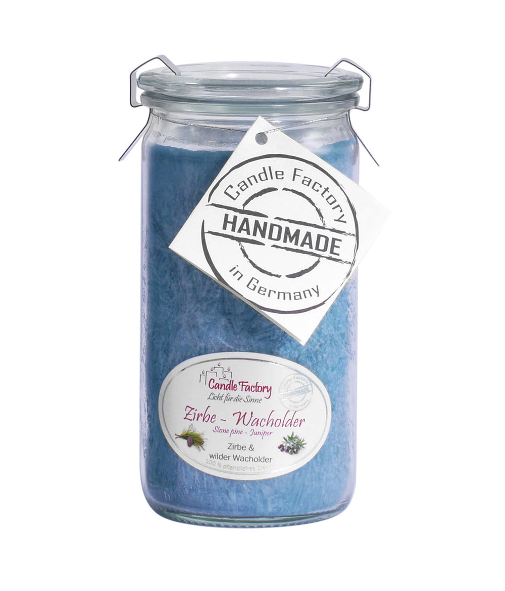 Blaue Duftkerze im Glas mit Etiketten „Zirbe-Wacholder“ und „Handmade in Germany“ auf weißem Hintergrund.