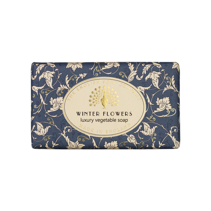 Blaue Seife mit weißem floralen Muster und goldfarbenem Etikett mit der Aufschrift „Winter Flowers – luxury vegetable soap“.