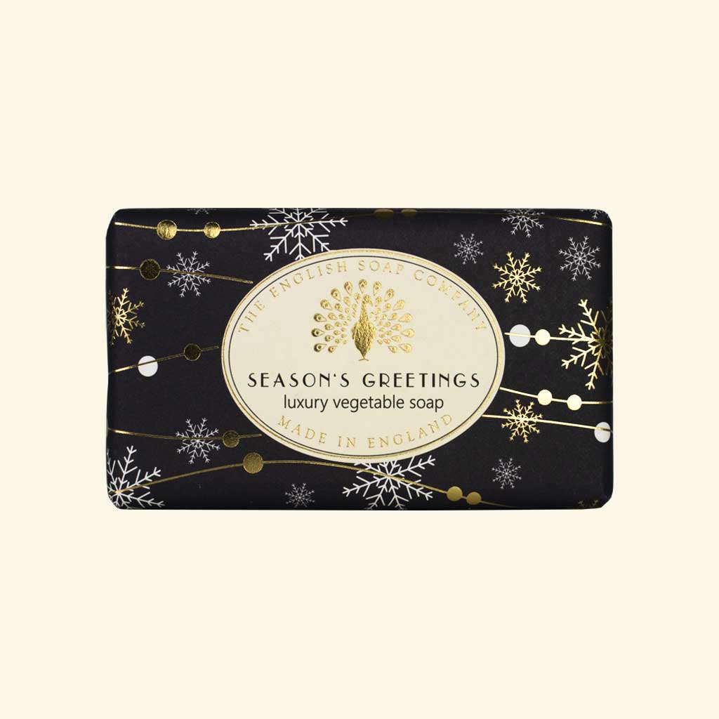 Schwarze Weihnachtsseife mit goldenen Schneeflocken und Aufschrift „Season’s Greetings – Luxury Vegetable Soap“ von The English Soap Company.