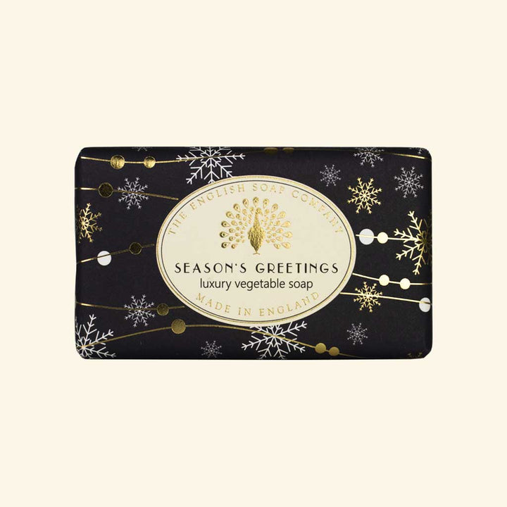 Schwarze Weihnachtsseife mit goldenen Schneeflocken und Aufschrift „Season’s Greetings – Luxury Vegetable Soap“ von The English Soap Company.