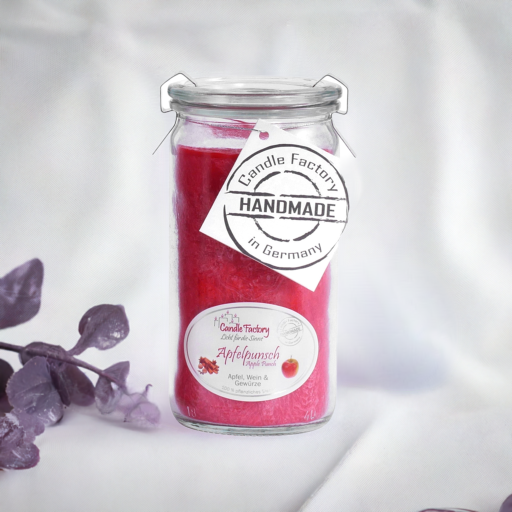 Rote Duftkerze im Glas mit Etiketten „Apfelpunsch“ und „Handmade in Germany“, daneben violette Dekozweige auf hellem Hintergrund.