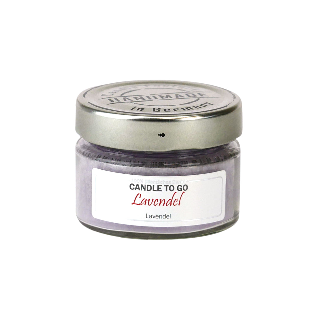 Lavendelfarbene Duftkerze „Candle to go Lavendel“ im kleinen Schraubglas mit silbernem Deckel, freigestellt auf Weiß.