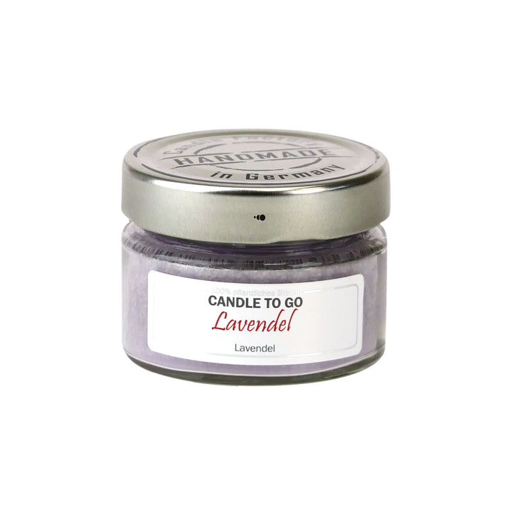 Lavendelfarbene Duftkerze „Candle to go Lavendel“ im kleinen Schraubglas mit silbernem Deckel, freigestellt auf Weiß.