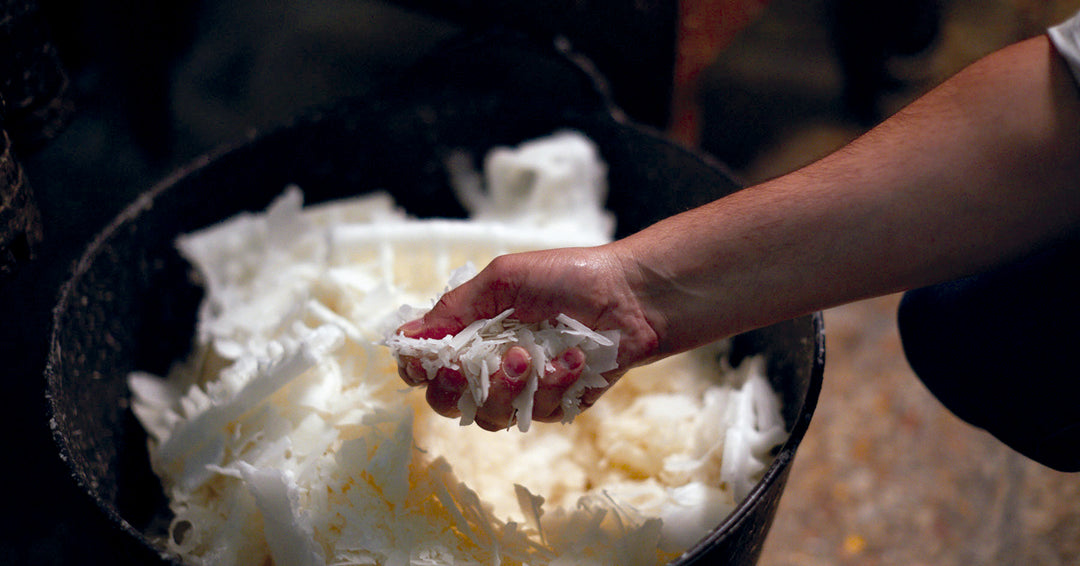 Hand hält weiße Wachsflocken während der handwerklichen Kerzenherstellung, Symbol für traditionelle Fertigung und Qualität bei Cereria Mollá 1899.