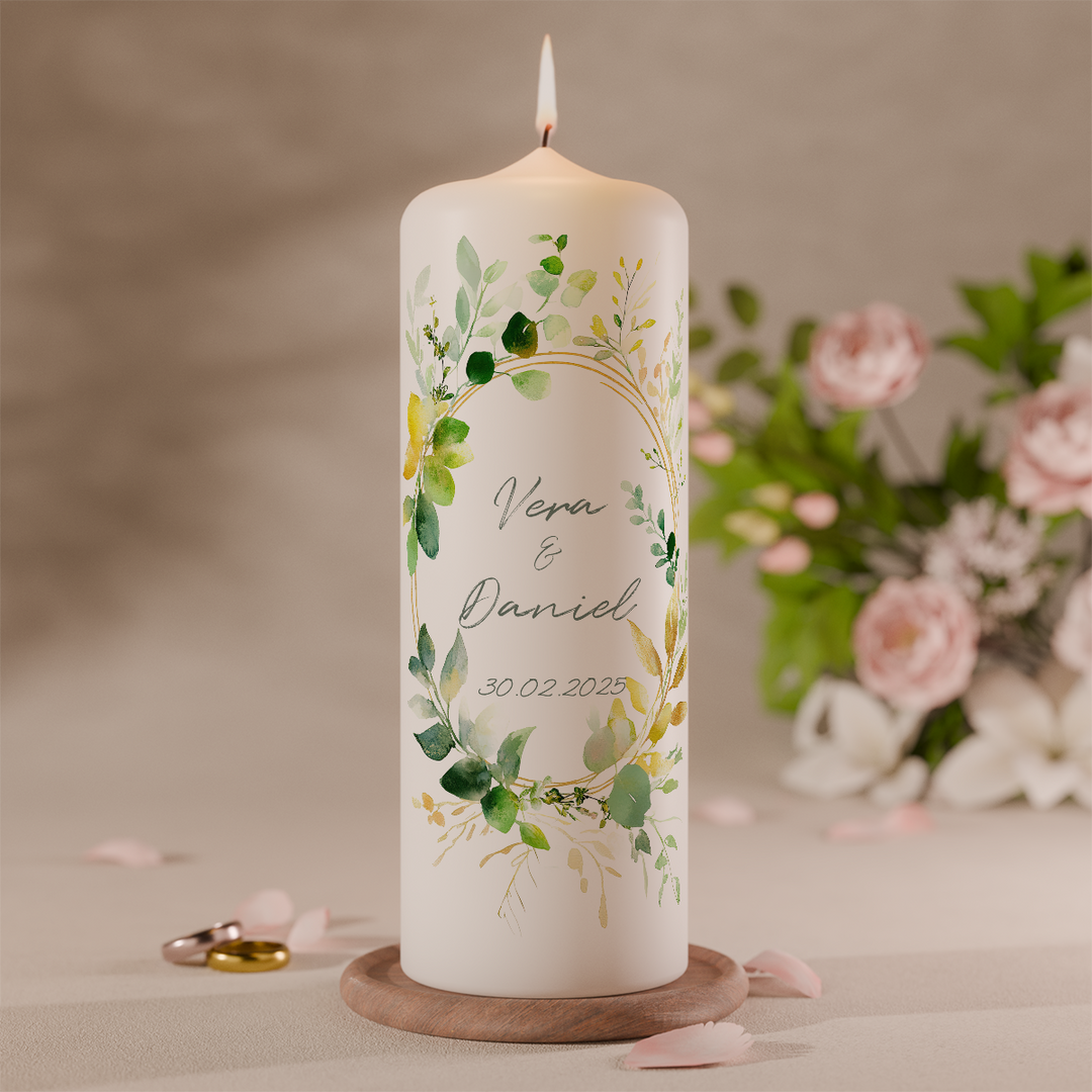 Hochzeitskerze mit Eukalyptusblättern in natürlichen Grüntönen personalisiert mit Namen und Datum vor Blumen