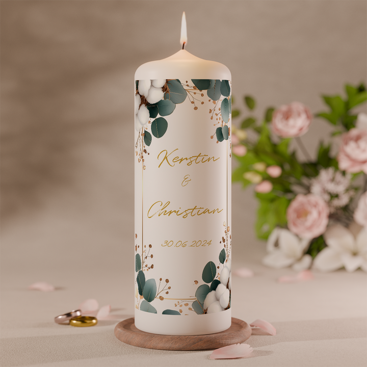 Detailaufnahme einer Hochzeitskerze mit grünen Eukalyptusblättern und zarter Blumendekoration