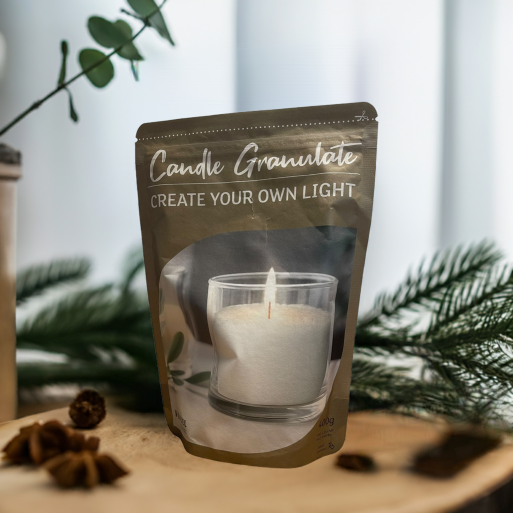Beutel mit Kerzengranulat „Create Your Own Light“, arrangiert mit Glas und Zapfen auf Holz