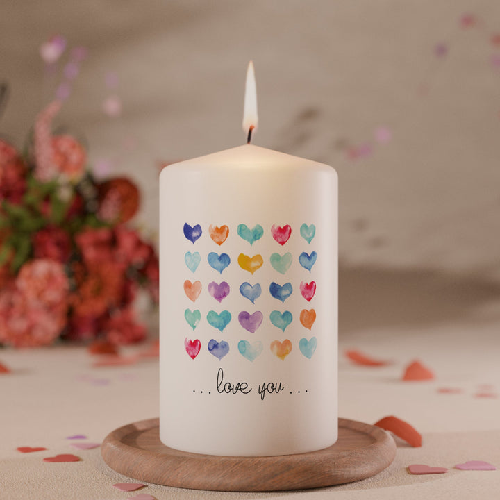 Weiße Kerze mit bunten Aquarell-Herzmotiven in Reihen und Schriftzug love you als liebevolle Geschenkkerze