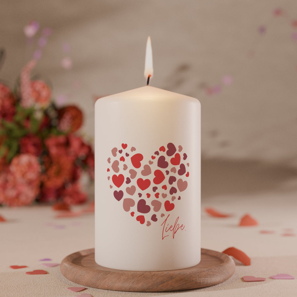 Weiße Kerze mit Herzmotiv aus vielen kleinen roten und rosafarbenen Herzen und Schriftzug Liebe