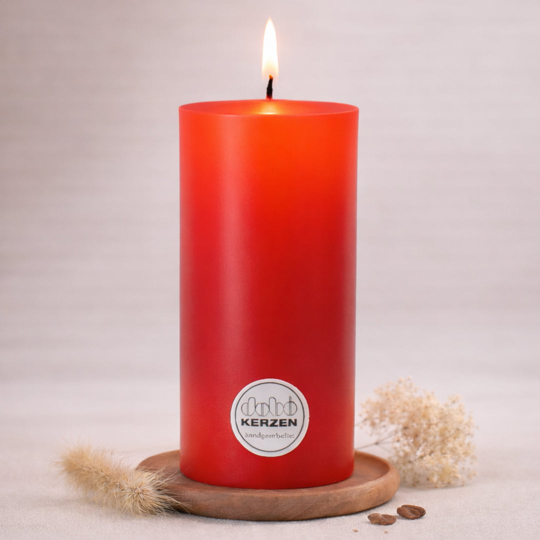 Rote Stumpenkerze handgefertigt von DOBO mit brennender Flamme auf Holzuntersetzer