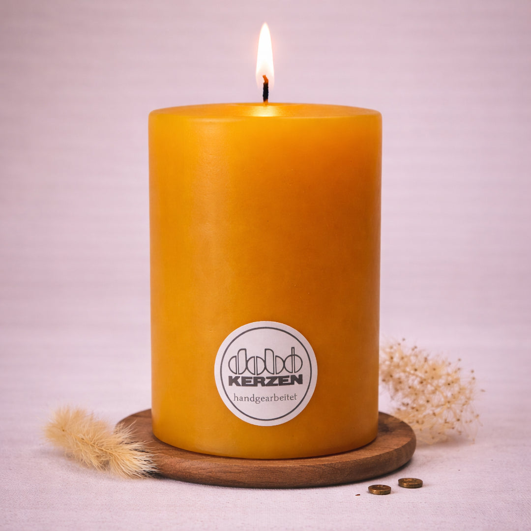 gelbe stumpenkerze handgefertigt dobo kerze brennend auf holzuntersetzer