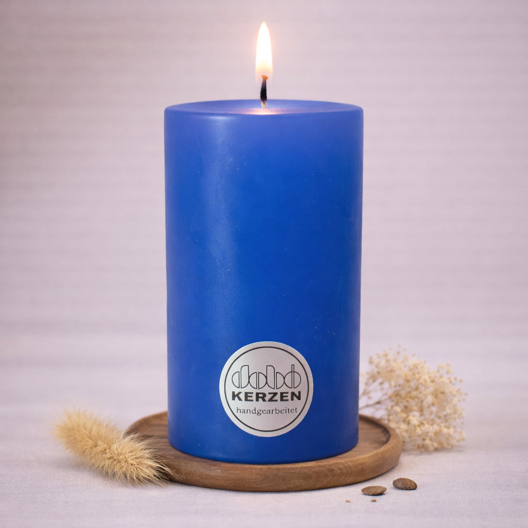 himmelblaue stumpenkerze handgefertigt dobo kerze brennend auf holzuntersetzer