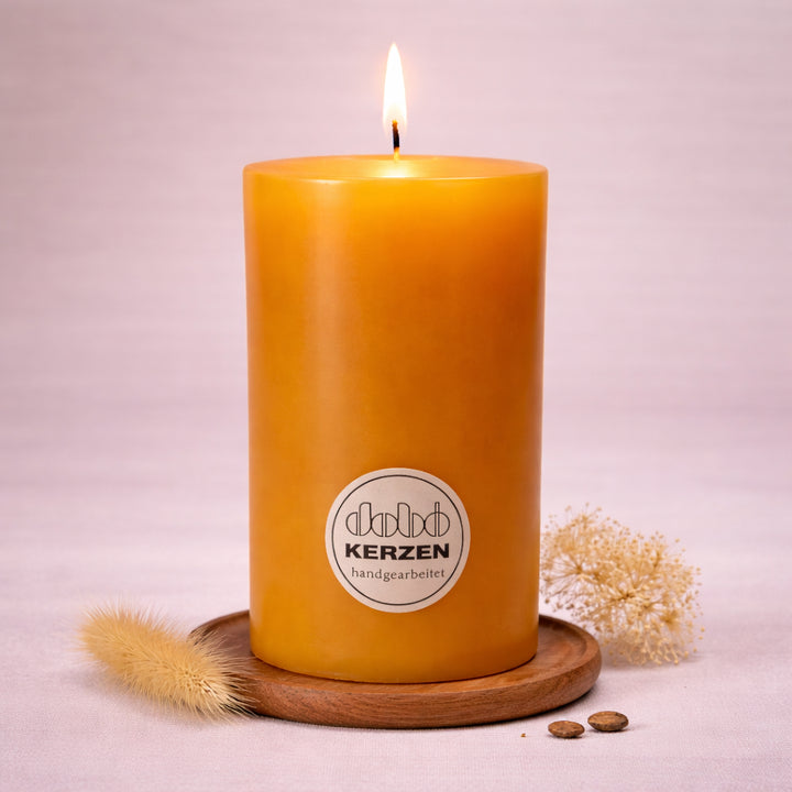 honigfarbene stumpenkerze handgefertigt dobo kerze brennend auf holzuntersetzer