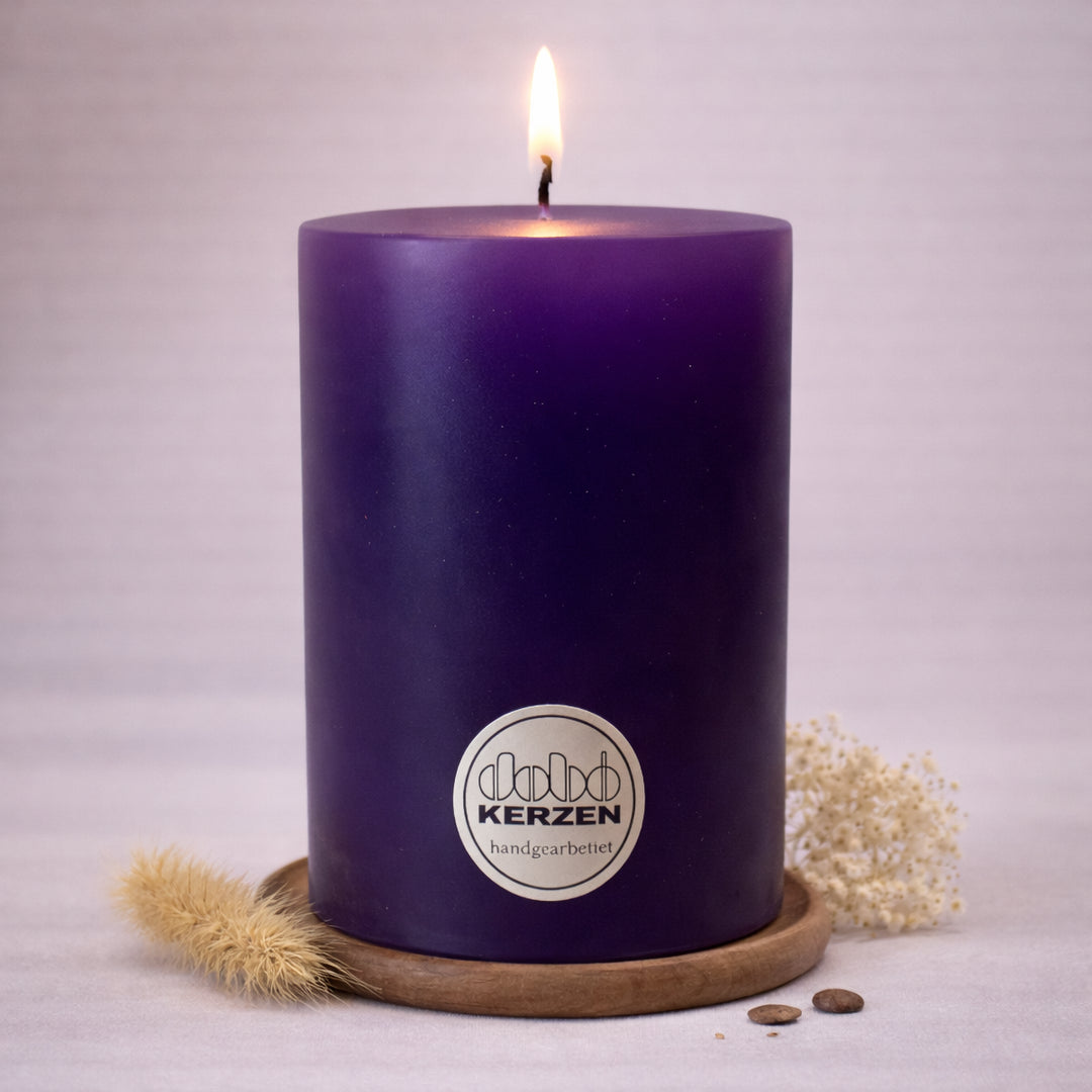 lilafarbene stumpenkerze handgefertigt dobo kerze brennend auf holzuntersetzer