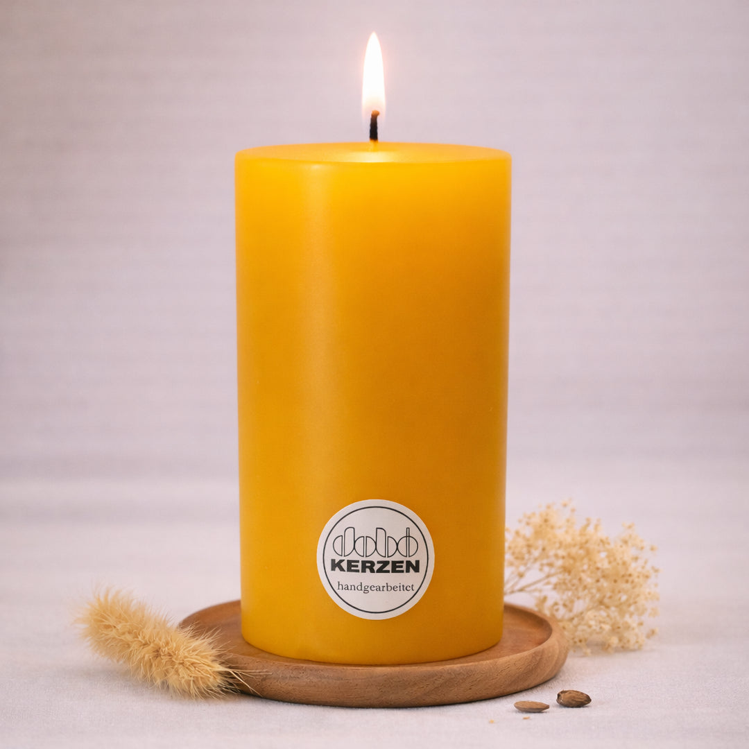 maisgelbe stumpenkerze handgefertigt dobo kerze brennend auf holzuntersetzer