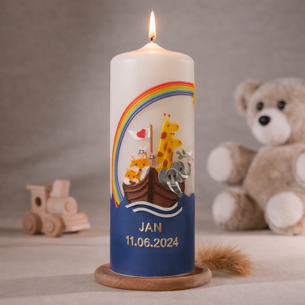 Elfenbeinfarbige Taufkerze mit Arche Noah, Regenbogen und Tiermotiven sowie Namensbeschriftung, brennend auf Holzsockel vor neutralem Hintergrund mit Teddybär