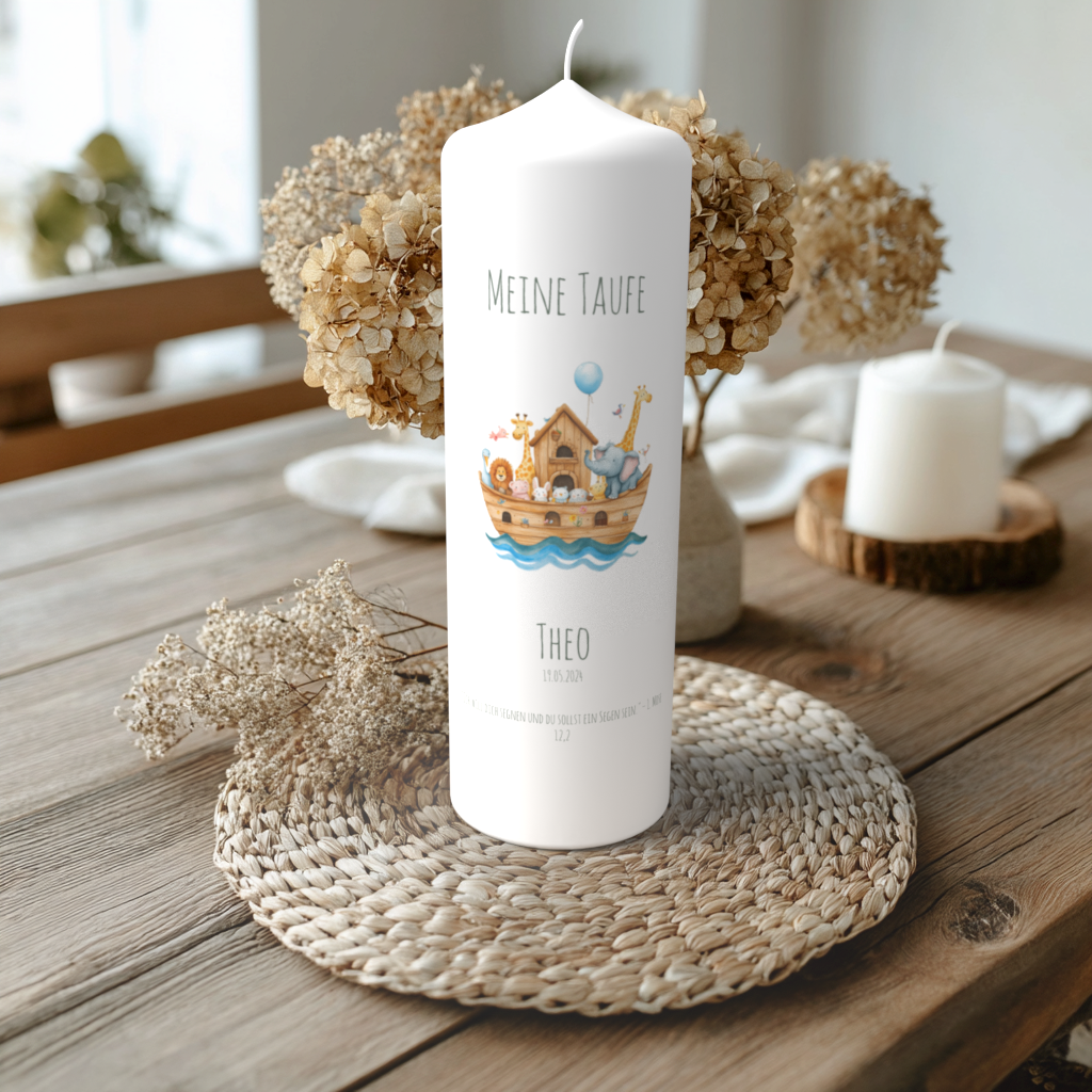 Handgefertigte Taufkerze mit Arche-Noah-Motiv und Name Theo, liebevoll fotografiert auf Holztisch mit Trockenblumen und Kerzenschein.