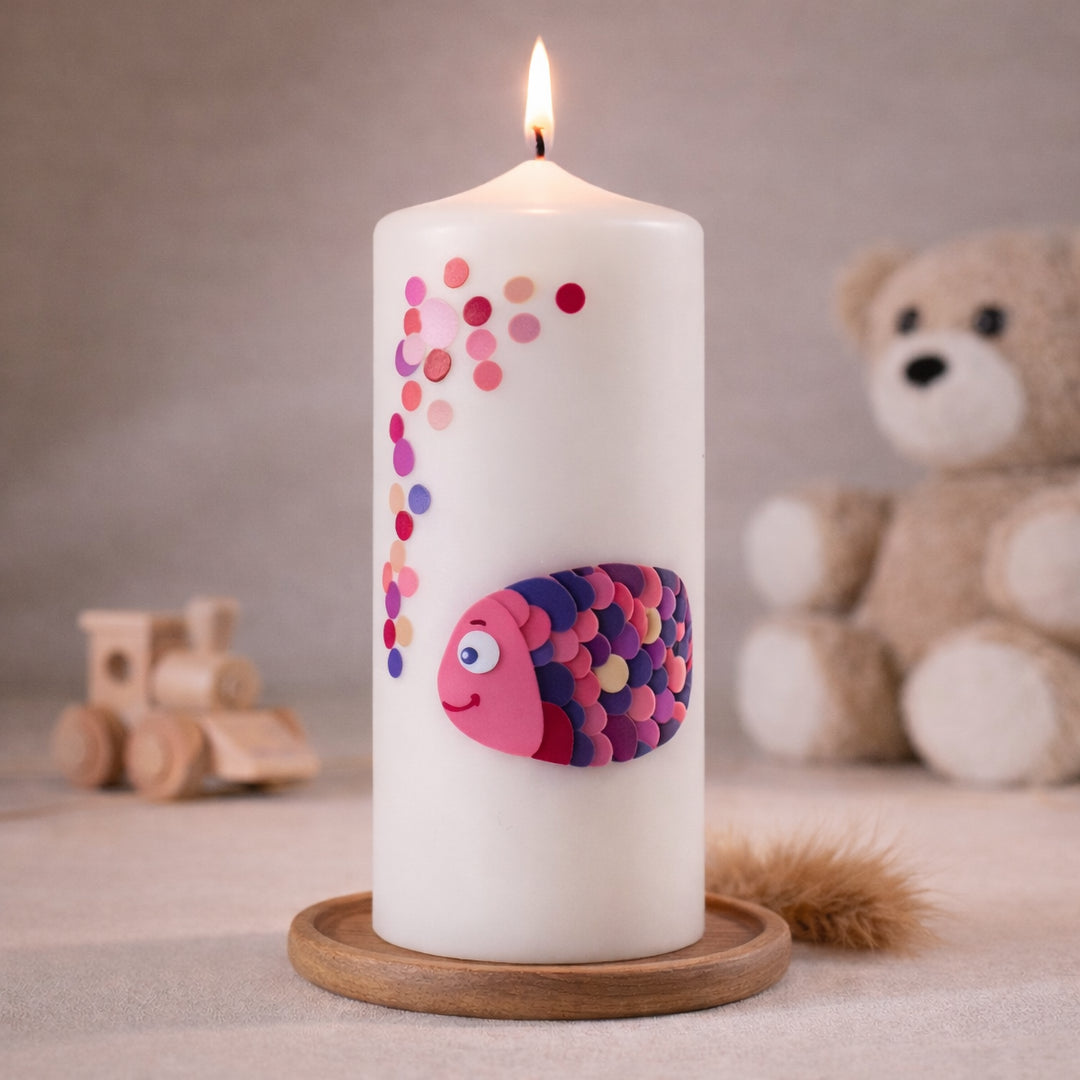 Weiße Taufkerze mit buntem Fischmotiv in Rosa und Lila, brennend auf Holzsockel vor neutralem Hintergrund mit Teddybär