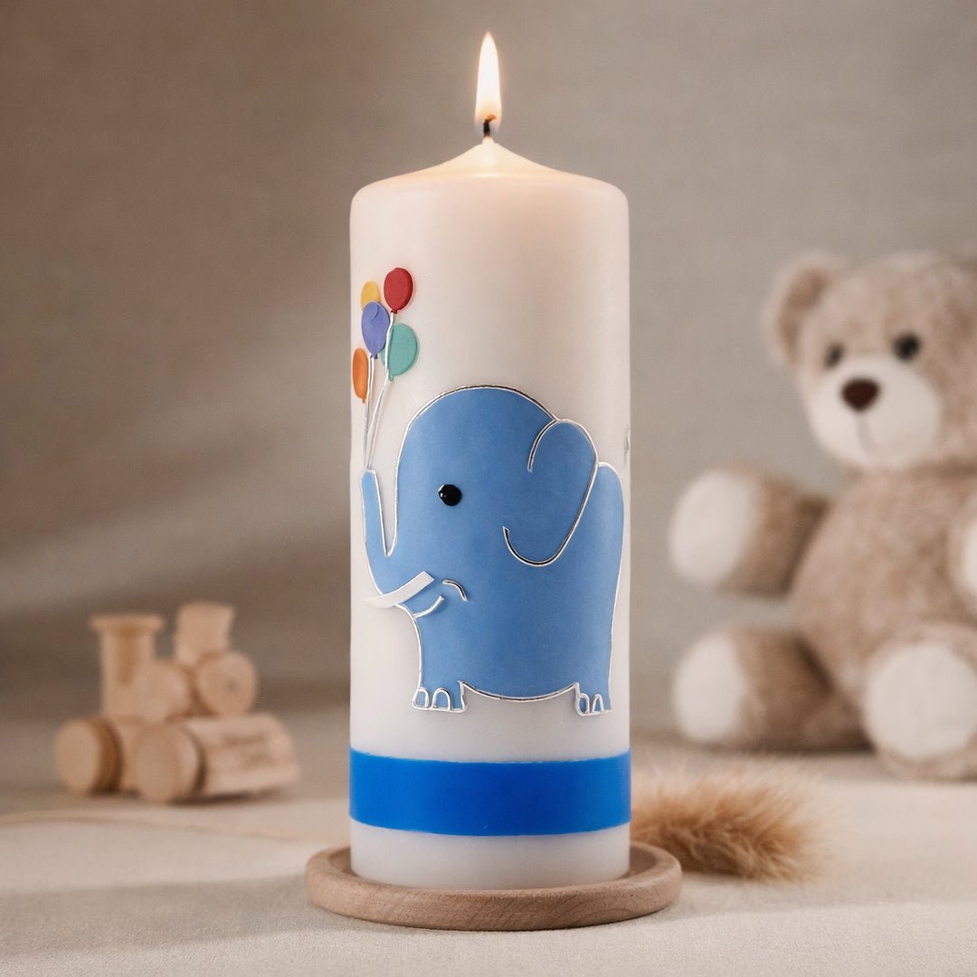 Weiße Taufkerze mit blauem Elefanten und bunten Luftballons sowie personalisiertem Namen und Datum, brennend auf Holzsockel vor neutralem Hintergrund mit Teddybär