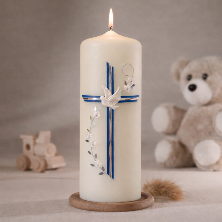 Elfenbeinfarbige Taufkerze mit blauem Kreuz, weißer Taube und floraler Ranke, stehend auf Holzsockel vor neutralem Hintergrund mit Teddybär