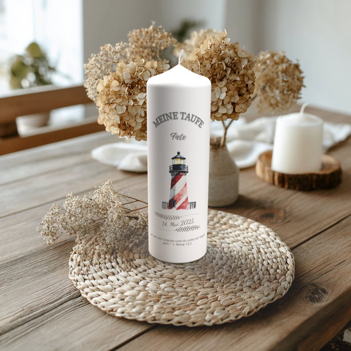 Handgefertigte Taufkerze mit Leuchtturm-Motiv und Name Fiete, auf Holztisch mit Trockenblumen arrangiert.