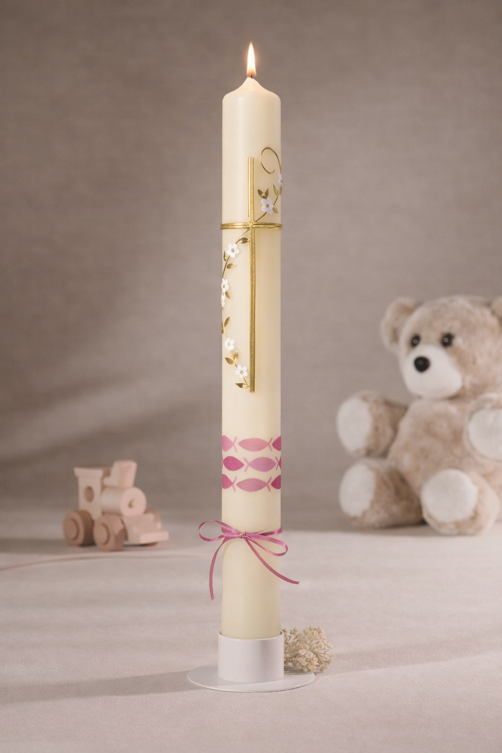 „Detailansicht einer Taufkerze mit goldenem Kreuz, rosa Fischen und zarter Blütenverzierung“