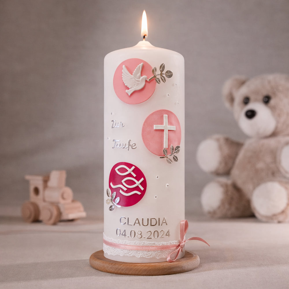 Weiße Taufkerze mit runden Zierelementen in Rosa, Taube, Kreuz und Fischsymbol sowie personalisiertem Namen und Datum, stehend auf Holzsockel vor neutralem Hintergrund mit Teddybär