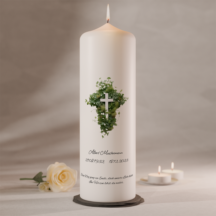Trauerkerze mit Herz aus Efeublättern und Kreuz auf weißer Gedenkkerze als Symbol für Hoffnung und Verbundenheit